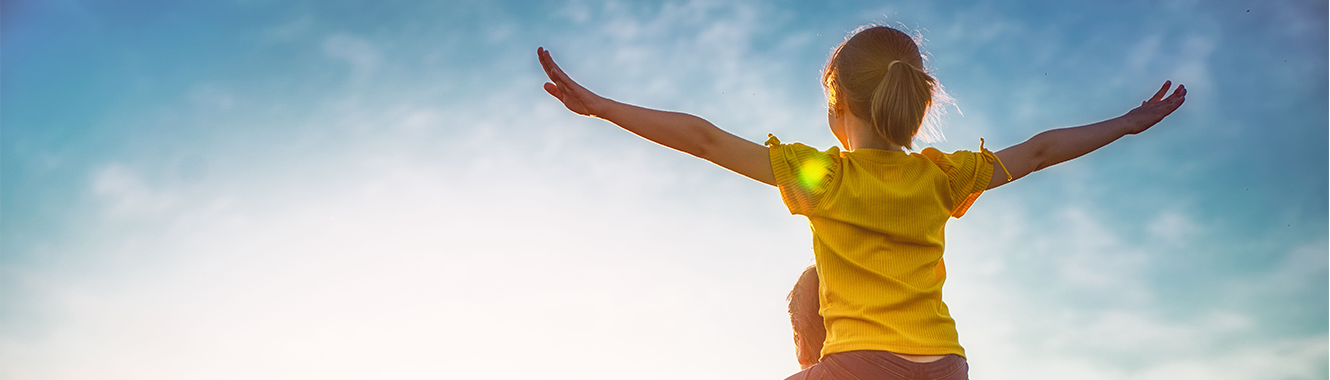 Young child on her father's shoulders, arms wide open.